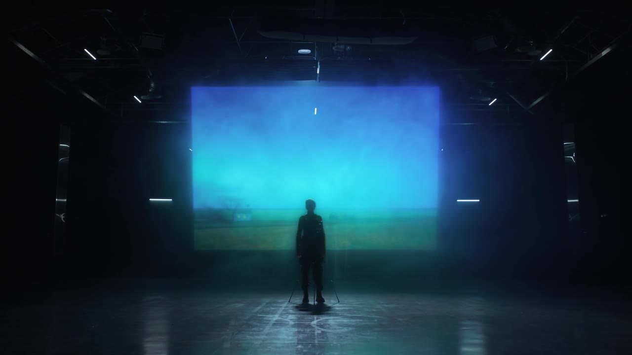 A lone figure before a projected landscape